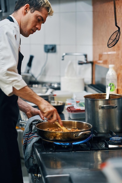 Cuoco unico che cucina con la padella sul fuoco