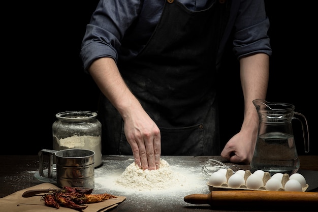 Cuoco unico che fa la pasta sulla tavola di legno