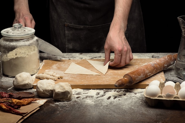 Cuoco unico che fa la pasta sulla tavola di legno