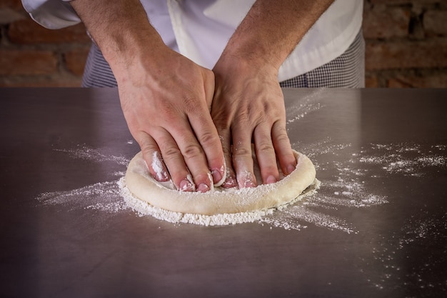 Cuoco unico che prepara la pasta della pizza nella cucina