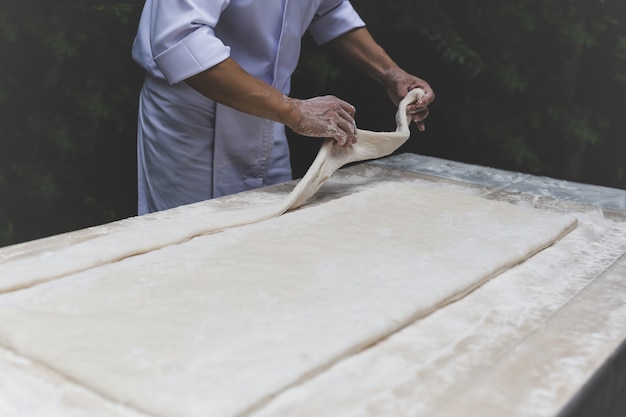 Cuoco unico che prepara pasta in cucina aperta nel giardino