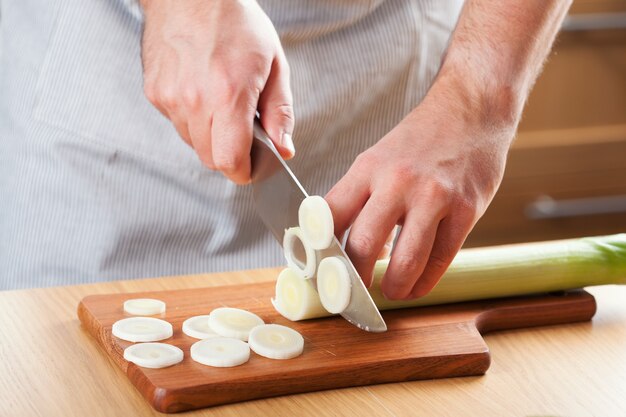 Cuoco unico che taglia il porro in cucina