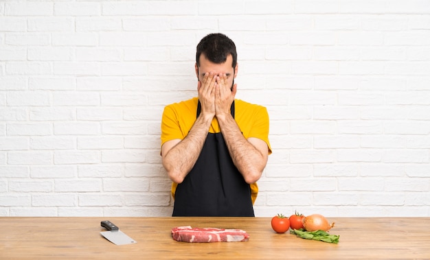 Cuoco unico che tiene in una cucina con espressione stanca e malata