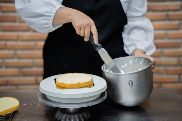 Cuoco unico della giovane donna che cucina dolce in cucina