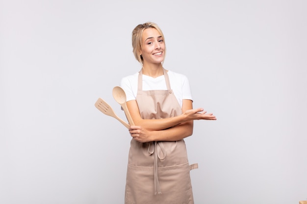 Cuoco unico della giovane donna che sorride allegramente, sentendosi felice e mostrando un concetto nello spazio della copia con il palmo della mano