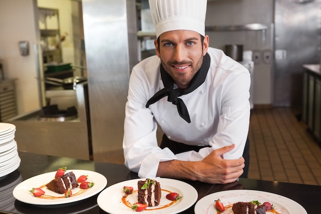 Cuoco unico felice che guarda l&#39;obbiettivo dietro il bancone di dessert