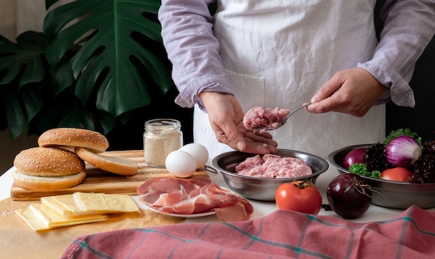 Cuoco unico femminile che cucina Big Burger o Cheeseburger e che tiene carne macinata.