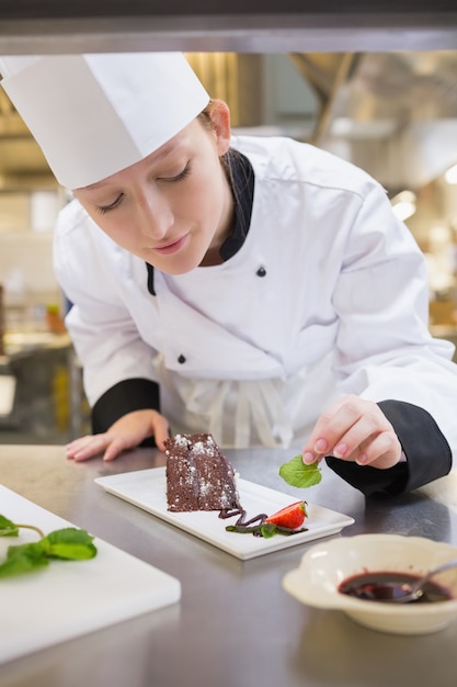 Cuoco unico femminile che mette la menta con la torta