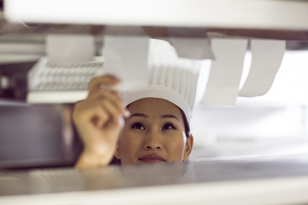 Cuoco unico femminile che passa la lista di controllo di cottura alla cucina