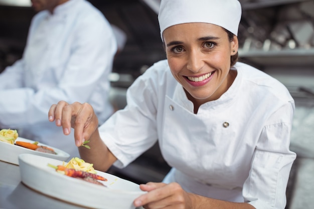 Cuoco unico femminile guarnire il cibo in cucina al ristorante