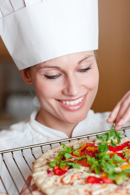 Cuoco unico femminile sorridente che prepara una pizza