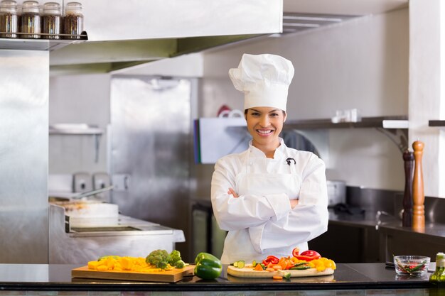 Cuoco unico femminile sorridente con le verdure tagliate in cucina