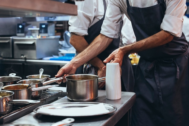 Cuoco unico irriconoscibile che cucina alimento in una cucina del ristorante