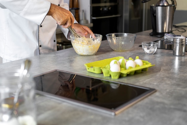 Cuoco unico maschio in cucina usando le uova per cucinare