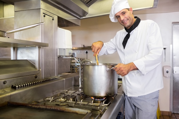 Cuoco unico maschio sorridente che prepara alimento in cucina