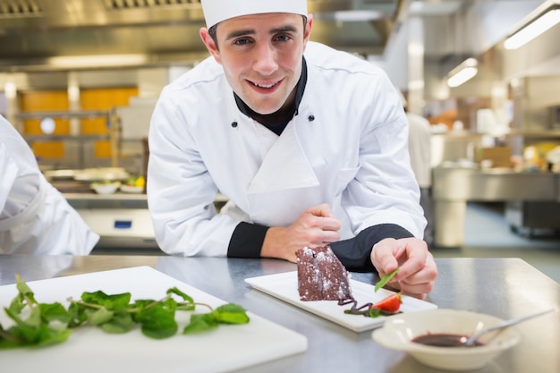 Cuoco unico sorridente che mette la menta con il suo dessert