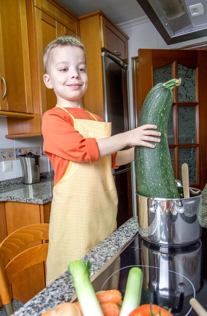 Cuoco unico sveglio che cucina grandi zucchine in una pentola