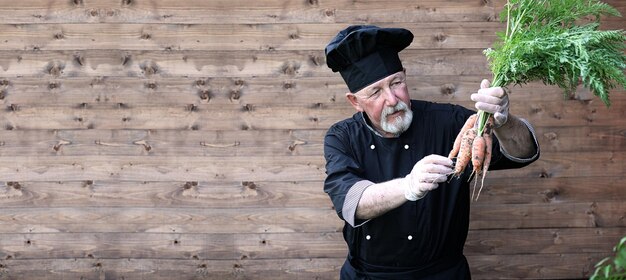 Cuoco vecchio in uniforme con le verdure