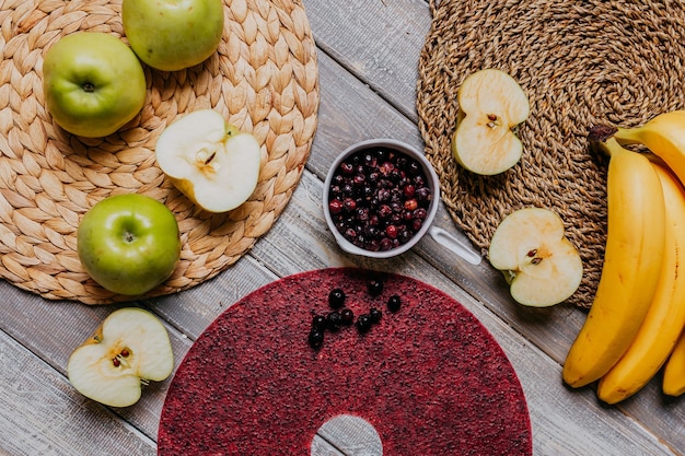 Cuoio di frutta di ribes nero con frutta fresca sul tavolo di legno. Pelle di frutta rossa rotonda con ribes nero. Cibo salutare. Mele, banane vista dall'alto.