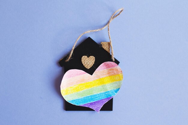 Cuore a forma di bandiera lgbt accanto a una casa giocattolo in miniatura.