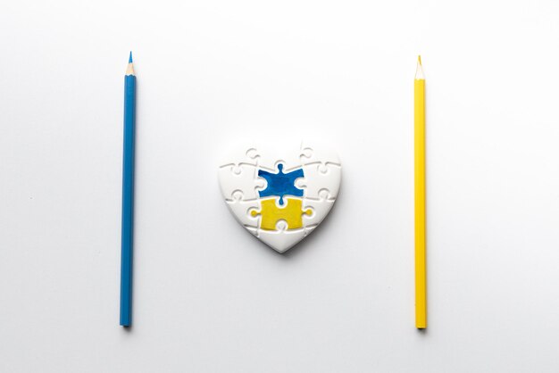 Cuore a forma di puzzle con i colori della bandiera dell'Ucraina con matite blu e gialle