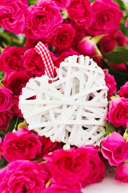 Cuore bianco decorativo fatto di viti Il giorno di San Valentino sullo sfondo di un mazzo di rose