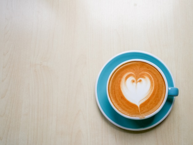 Cuore caldo dell&#39;illustrazione del caffè in tazza blu su struttura di legno