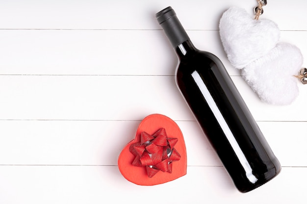 Cuore, candela, bottiglia di vino su superficie di legno bianca. Concetto di San Valentino. Disteso