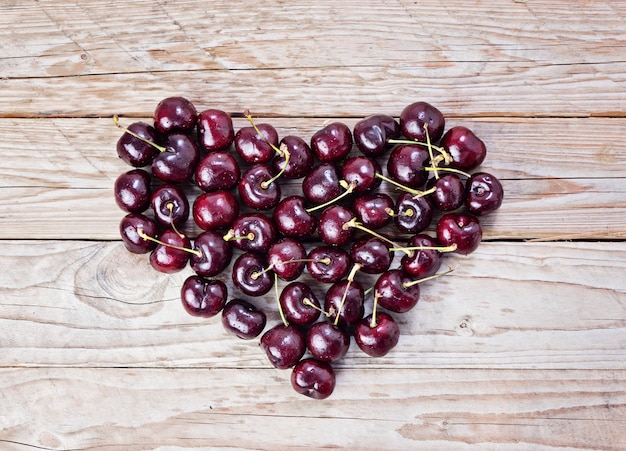 Cuore dalla ciliegia fresca e matura su un fondo di legno