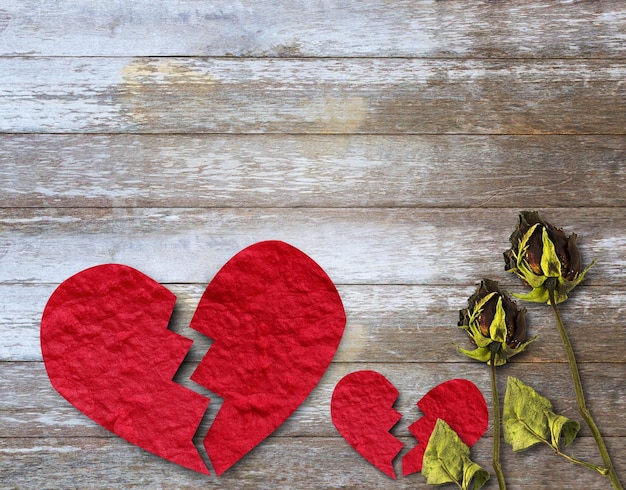 Cuore di carta rosso rotto e rosa secca sul tavolo di legno