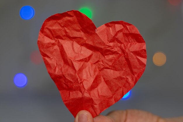 cuore di carta stropicciata in mano di donna su sfondo grigio spazio per il testo amore spezzato concept