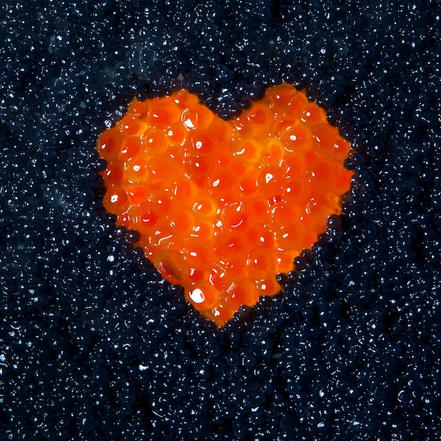 Cuore di caviale rosso su sfondo di caviale nero