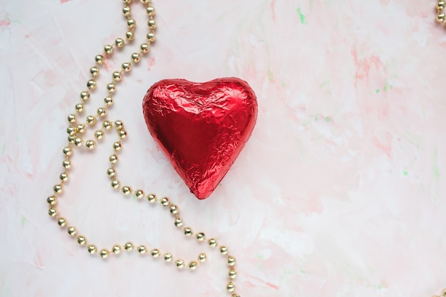 Cuore di cioccolato in lamina rossa su una rosa