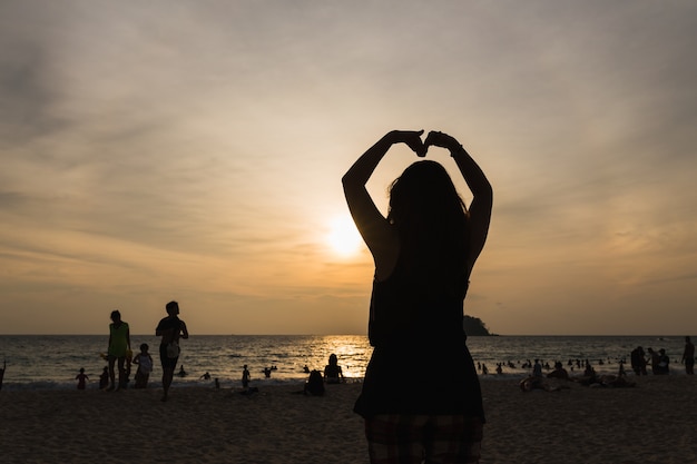 Cuore di donne al tramonto sulla spiaggia