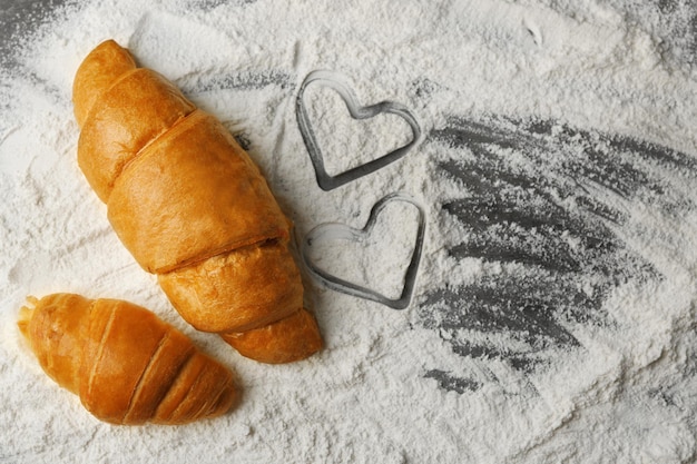 Cuore di farina e croissant freschi su fondo di legno