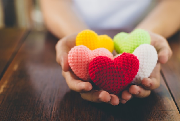 Cuore di filato di colori misti sul dare le mani. Close up di colorati fatti a mano.