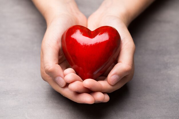 Cuore di legno rosso nelle mani del bambino.