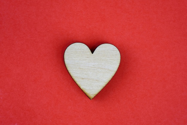 Cuore di legno su fondo rosso, simbolo dell'amore.