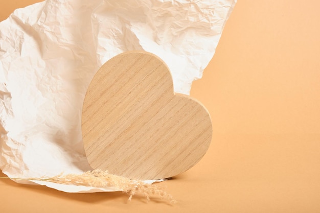 Cuore di legno su sfondo bianco di carta stropicciata, sfondo beige, sfondo simulato per la presentazione del prodotto