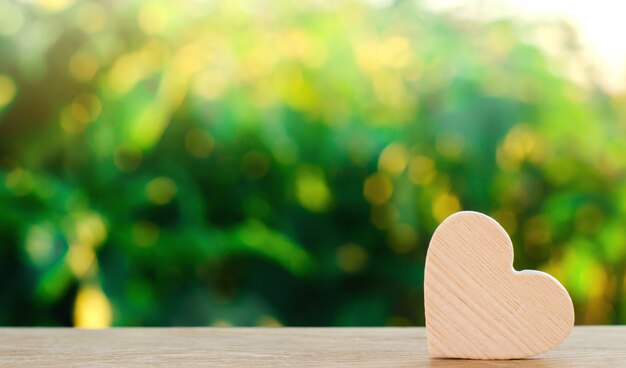 Cuore di legno sul fondo verde del bokeh Concetto di amore e romanticismo. A forma di cuore.