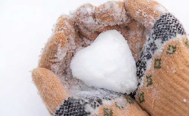 Cuore di neve nel fuoco selettivo delle mani