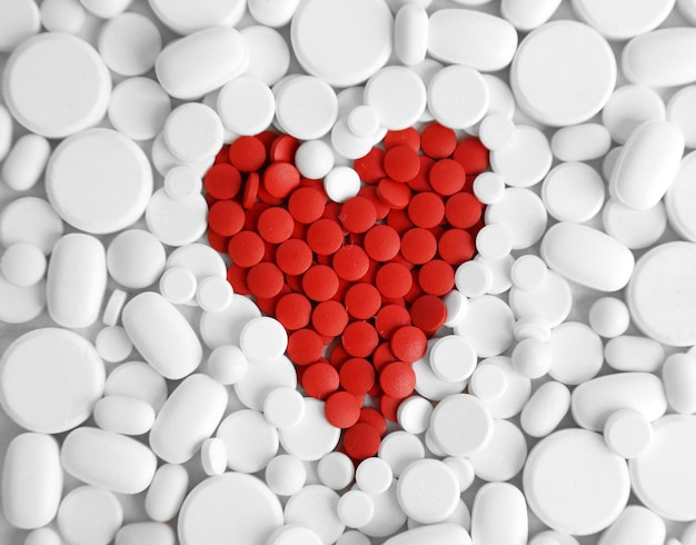 Cuore di pillole rosse su sfondo bianco pillole