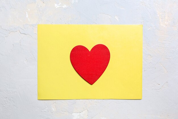 Cuore dipinto di rosso su carta gialla, carta minimalista di San Valentino nel colore dell'anno