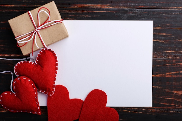 Cuore e regalo fatti a mano del feltro rosso, accanto a Libro Bianco, sulla tavola di legno