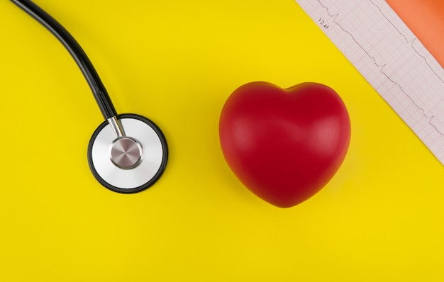 Cuore giocattolo e uno stetoscopio su sfondo giallo Vista dall'alto Cardiologia cura del cuore