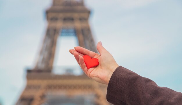 Cuore nelle mani vicino alla Torre Eiffel a Parigi. Messa a fuoco selettiva.