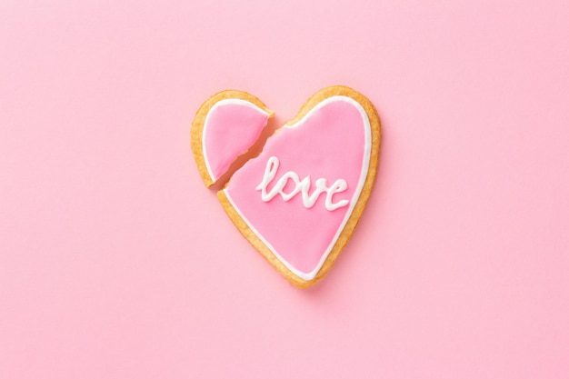 Cuore rosa biscotto rotto con la parola AMORE, vista dall'alto, piatto. Concetto di rottura o divorzio.