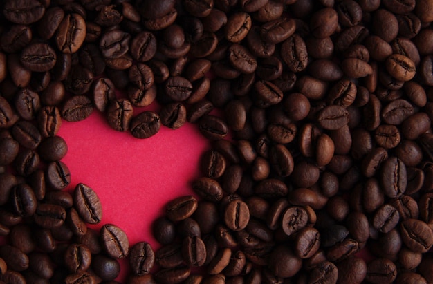 Cuore rosa su uno sfondo di chicchi di caffè il giorno di San Valentino