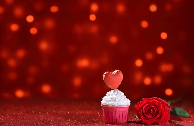 Cuore rosso brillante sulla parte superiore del muffin per San Valentino con fiore di rosa come una dolce dichiarazione d'amore. Copia spazio