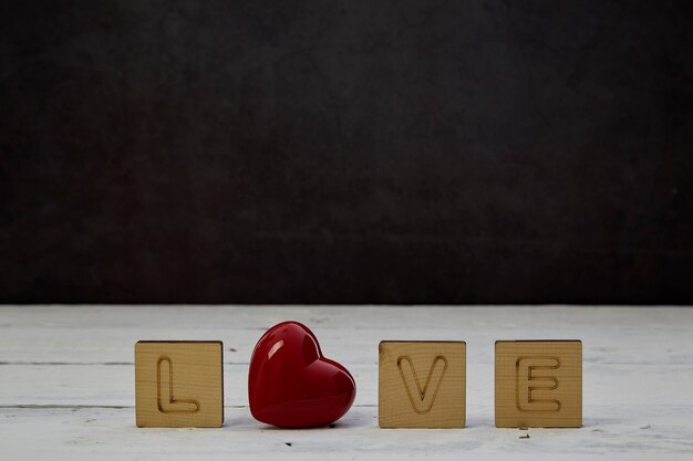 Cuore rosso con blocco di legno vuoto su legno bianco